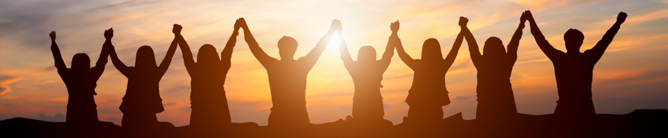 People holding hands in the air with sunset background
